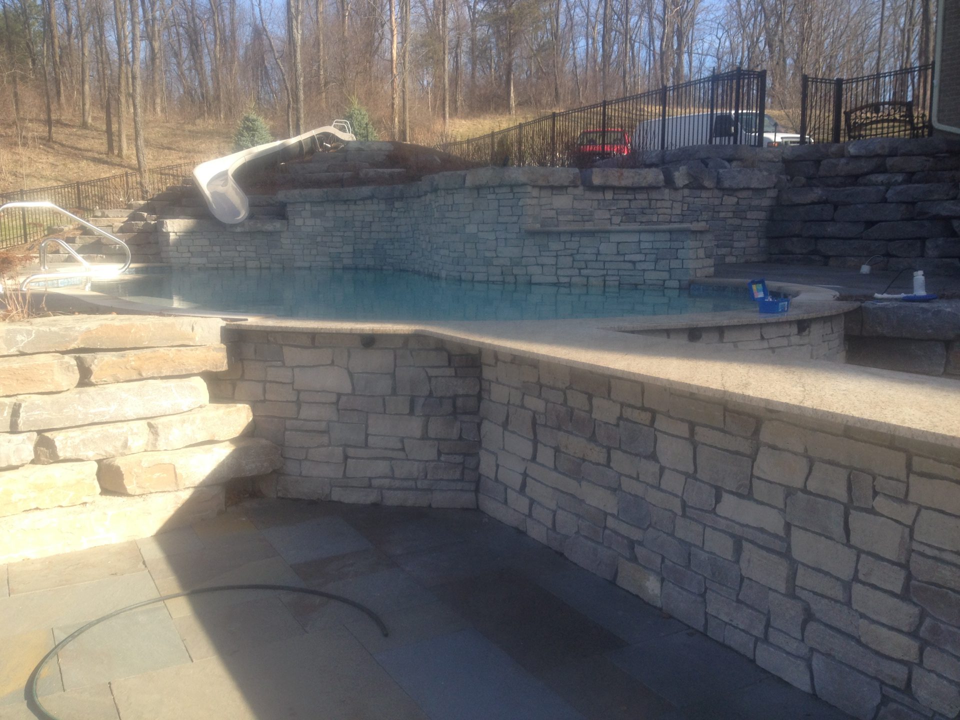 Elevated pool with stone retaining wall and slide